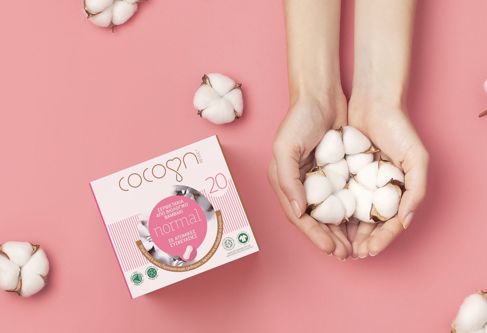 Cocoon biodegradable sanitary pads carton box next to hands holding cotton