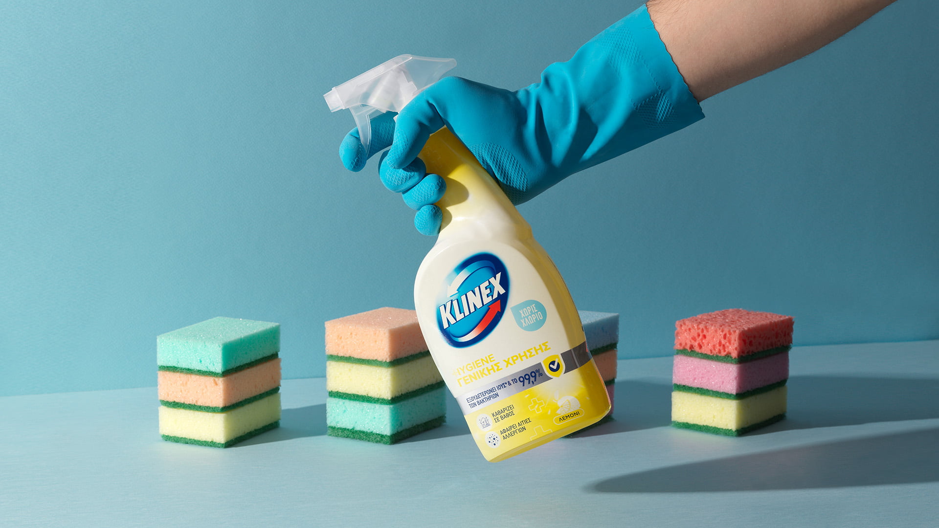 Hand with glove holding Klinex Hygiene Spray next to stack of sponges