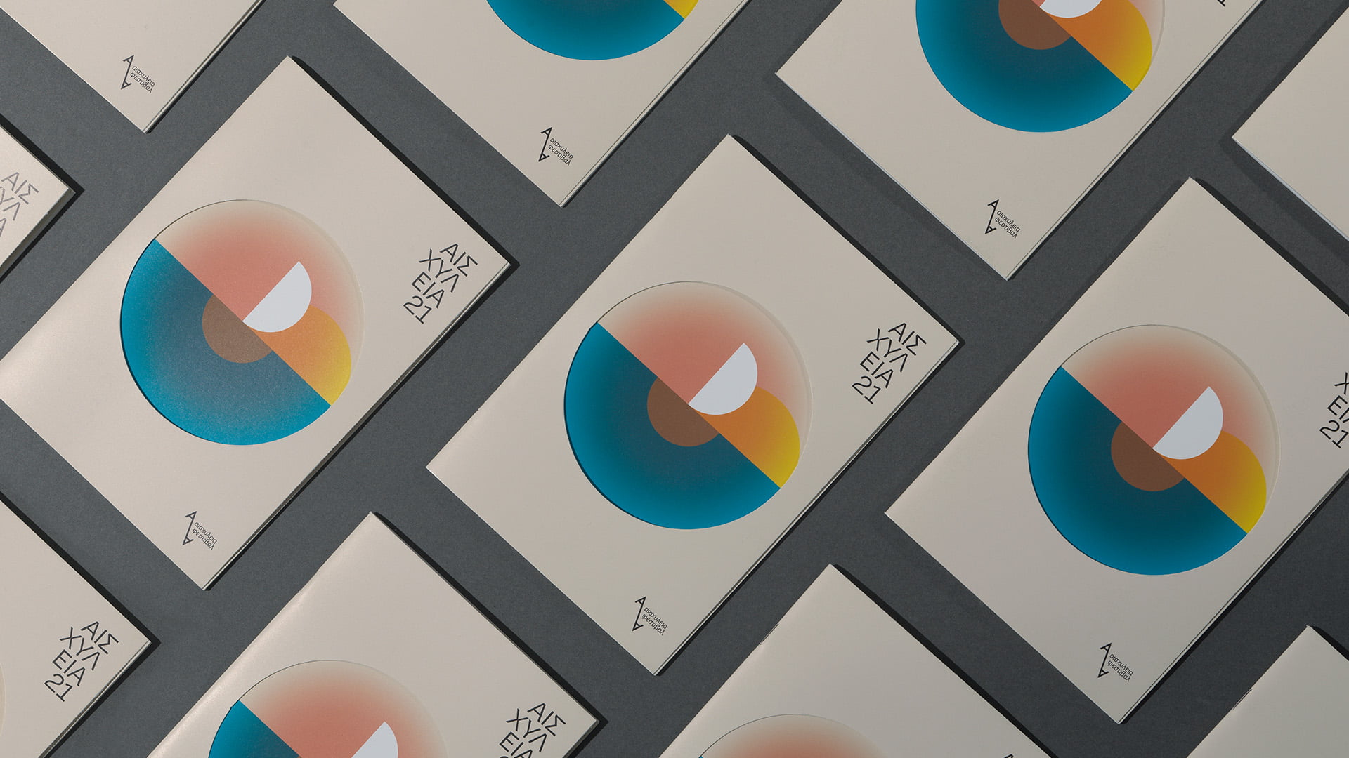 A flat lay pattern of the Aeschylia Festival 2021 print materials (likely brochure covers or vinyl sleeves), showing the minimalist, colorful geometric circle graphic repeated diagonally on a dark grey background.