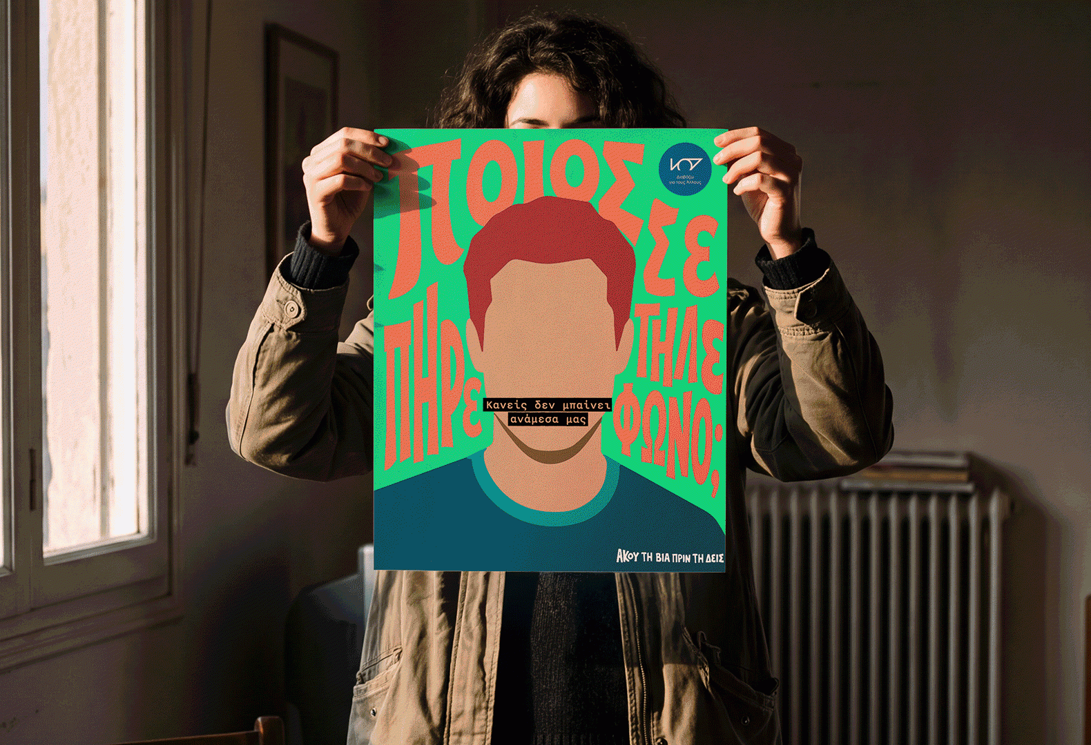 Woman holding a colourful Raise Her Voice illustrated poster in front of their face beside a window.